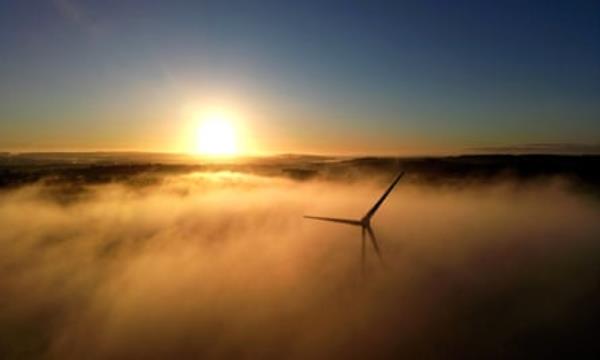 A wind turbine shrouded in fog