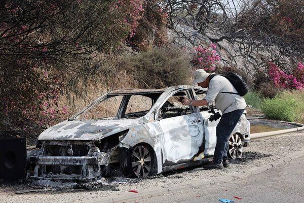 A man takes pictures of a car burned during an infiltration by Palestinian militants from the Gaza Strip, a day after the attack near the southern city of Sderot on October 8, 2023.  (Photo by JACK GUEZ/AFP via Getty Images)
