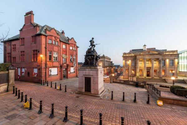 Illuminated view of Town hall in a Yorkshire Street with War memorial Sculpture in Oldham.